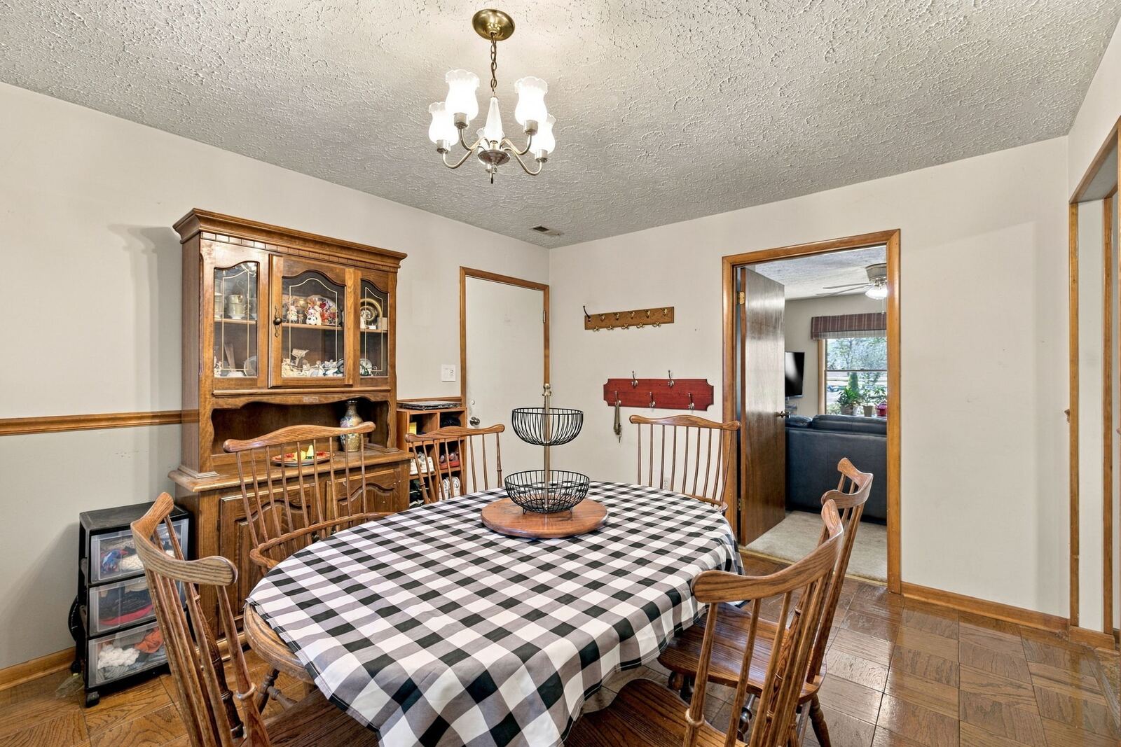 Dining room with a chandelier, a round table and chairs, a china cabinet and a doorway to the kitchen.