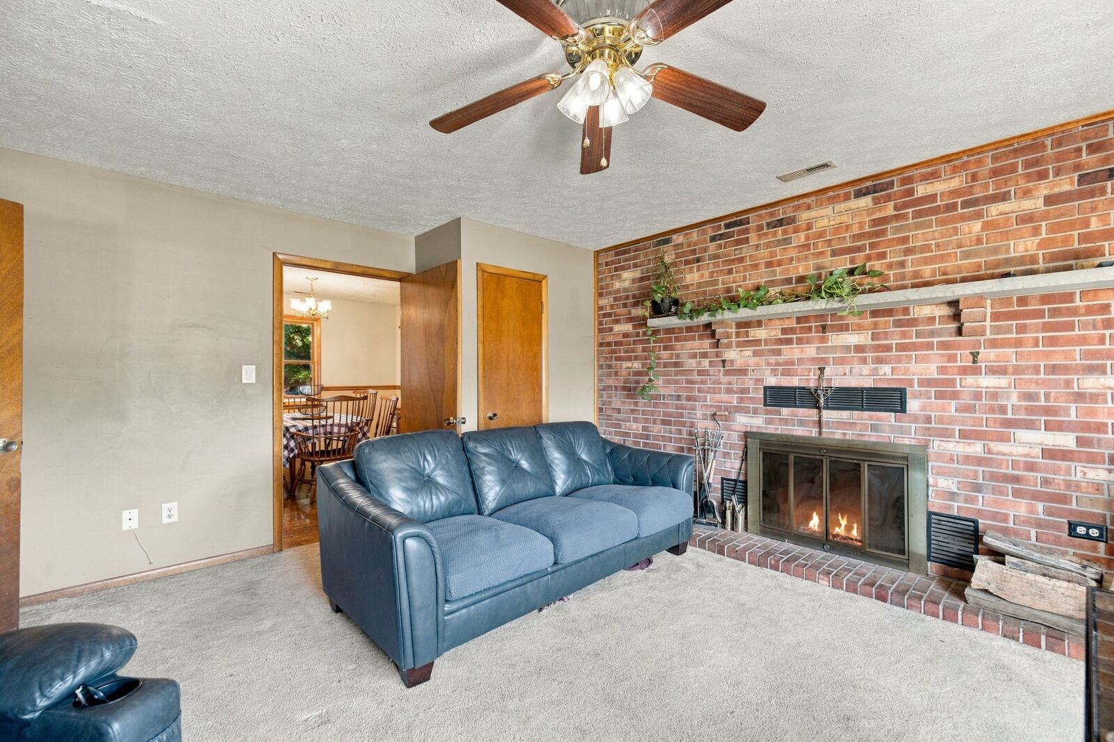 Brick fireplace with glass doors and a long mantel shelf in the family room, beside a doorway to the dining room.
