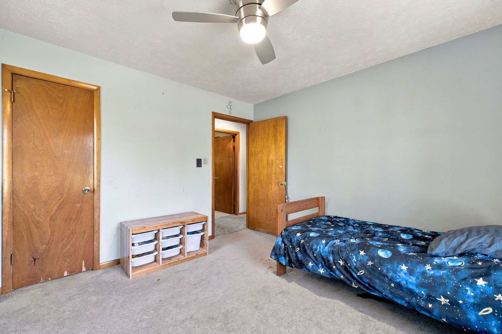 Bedroom with light blue walls, a twin bed, a closet door and a doorway to the hall.