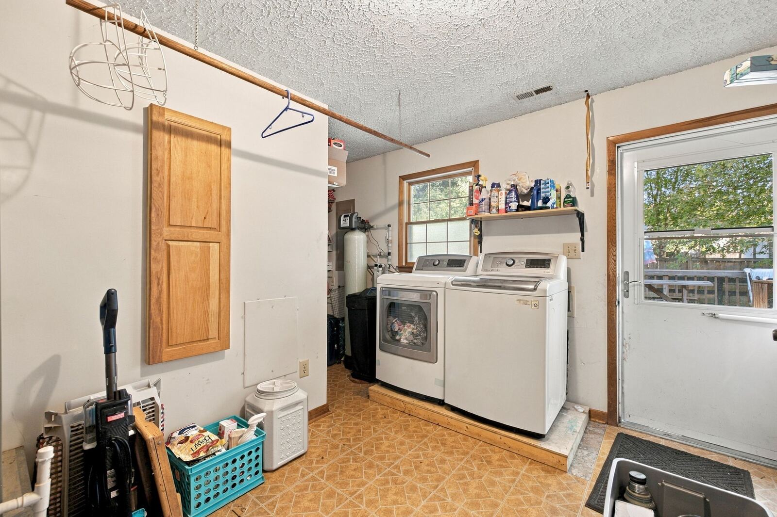 Laundry room with a washer and dryer, a wall shelf, a window and an exterior door.