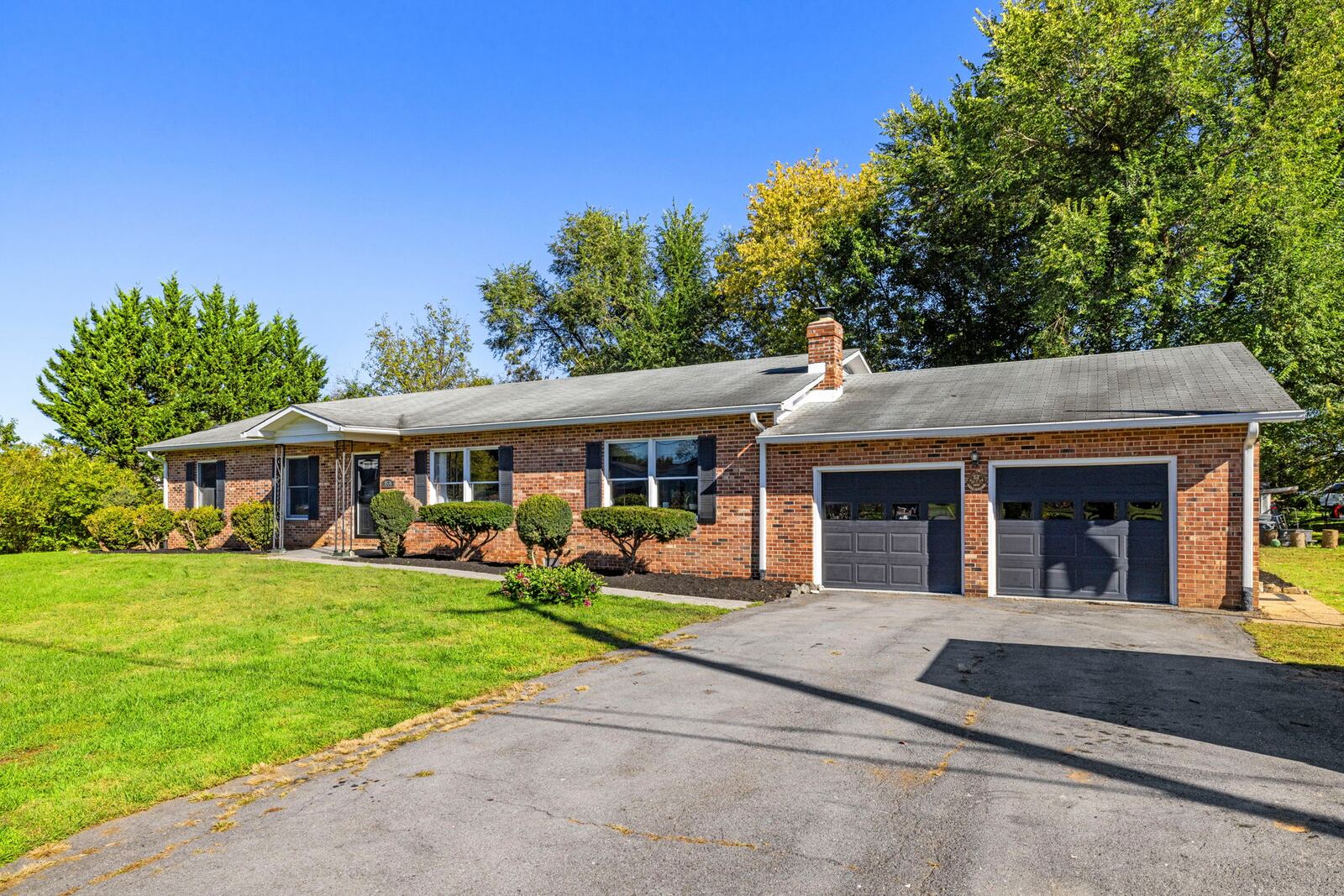 Attached two-car garage with dark garage doors and a paved driveway beside the brick home.